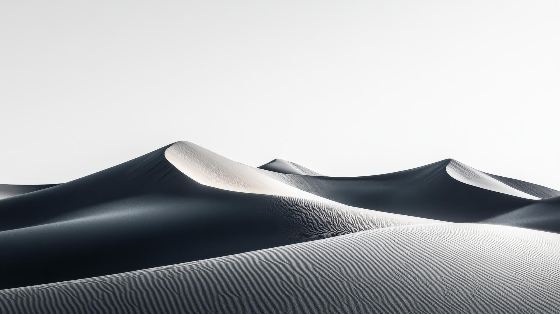 A sprawling desert with rolling sand dunes under a clear sky, in black and white wallpaper.