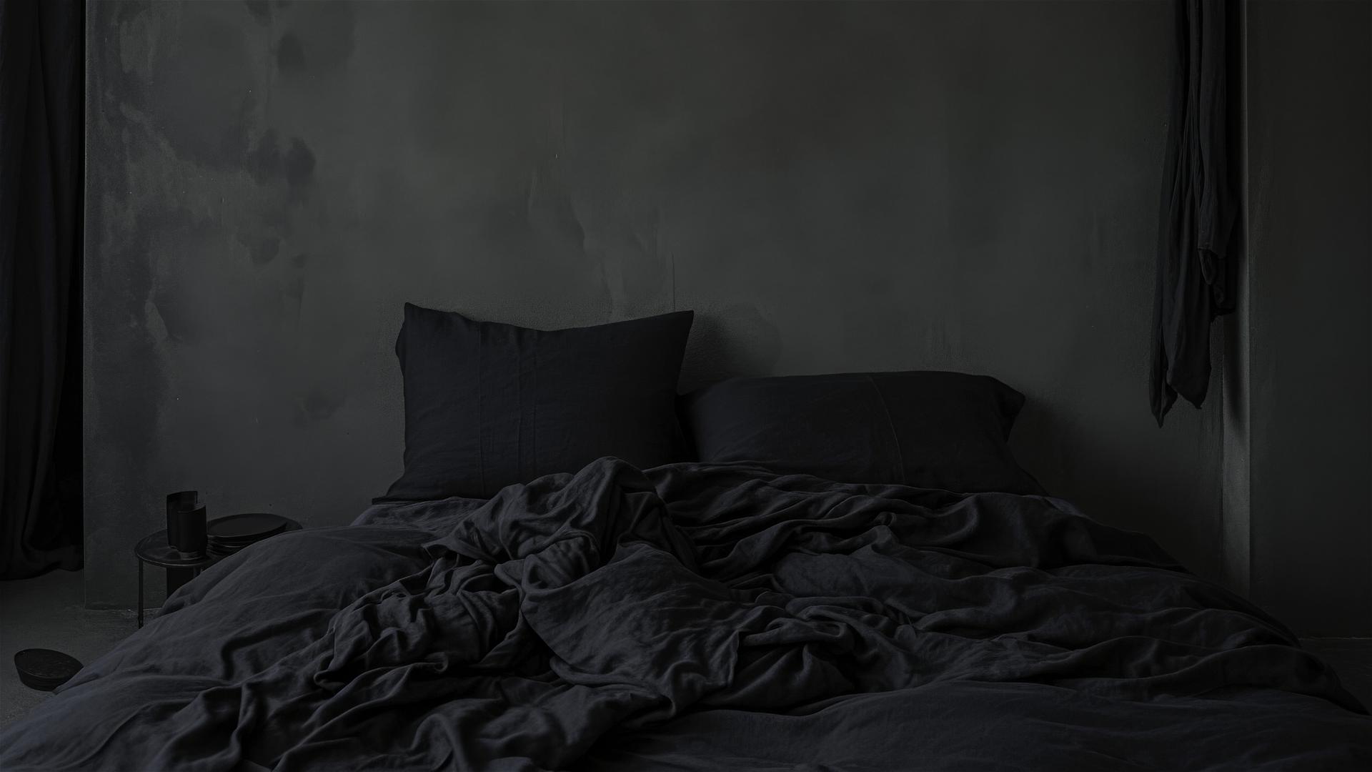Aesthetic dark bedroom with black silk sheets and a single dark pillow, the fabric's sheen catching the light, intimate and stylish