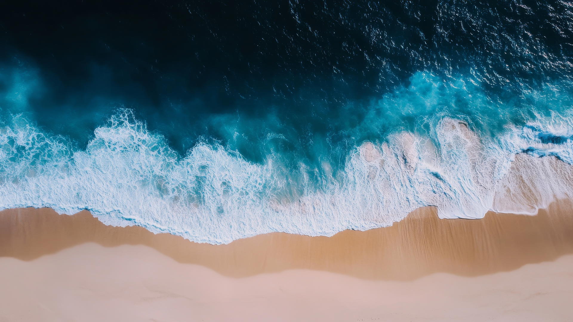 Overhead drone shot of a beach showing smooth white sand and deep blue ocean waves, beach pictures wallpaper