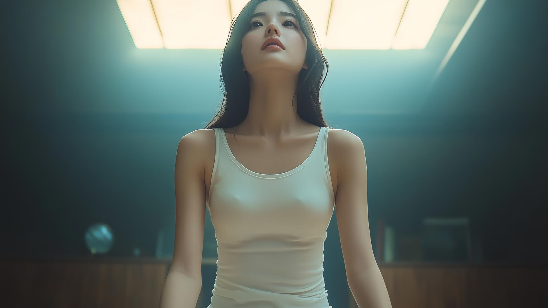 Low angle shot of an Asian girl in a white t-shirt, kneeling and looking down.
