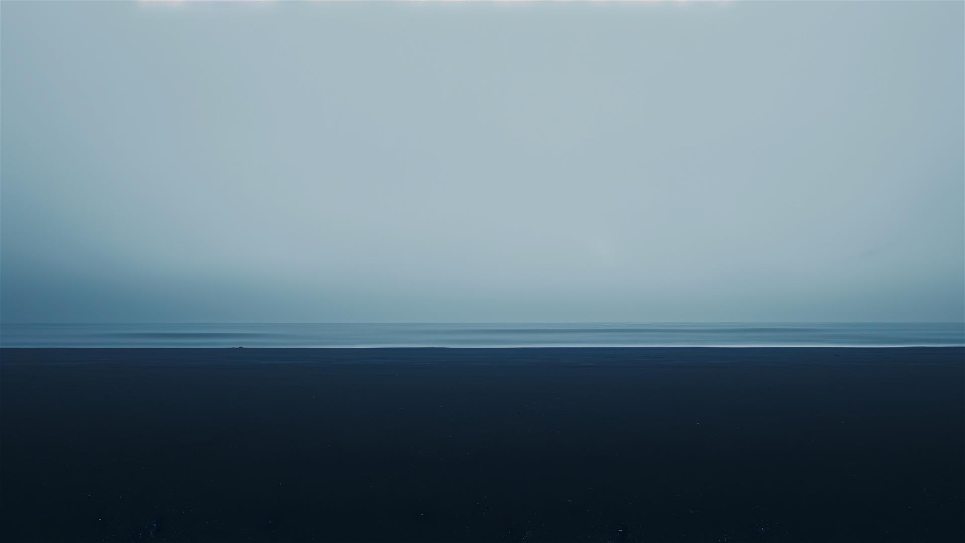 Monochrome sky and sea blending on dark pebble beach in somber morning