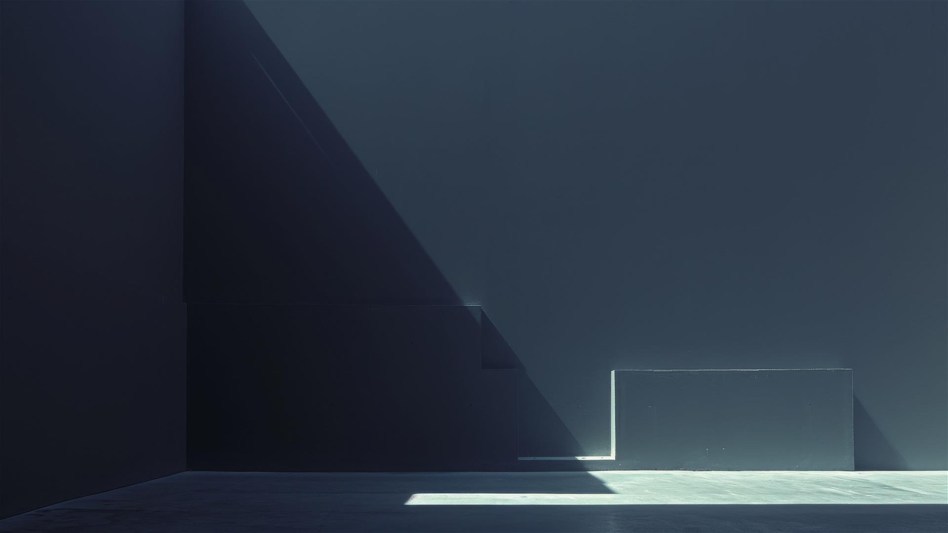 Aesthetic dark room with converging shadows and a single light spot on the floor