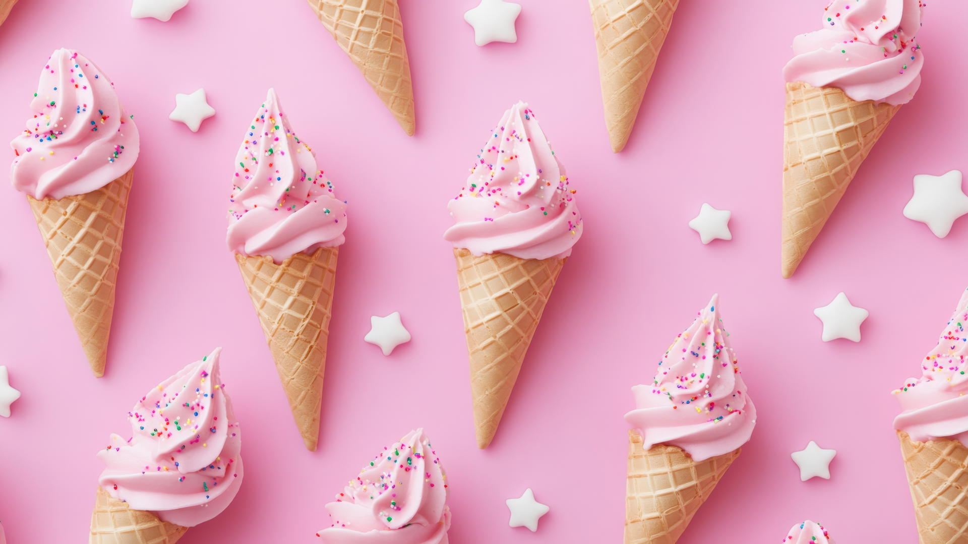 Preppy pink wallpaper featuring playful pattern of pink ice cream cones with sprinkles