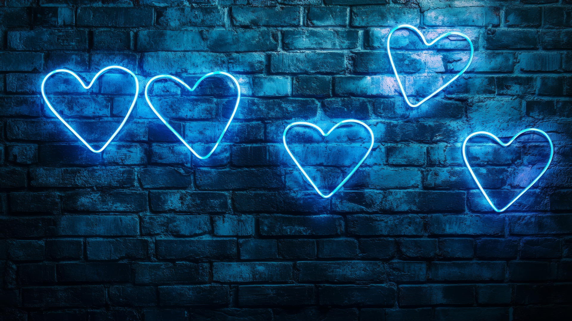 Blue heart wallpaper with neon blue heart signs on a brick wall