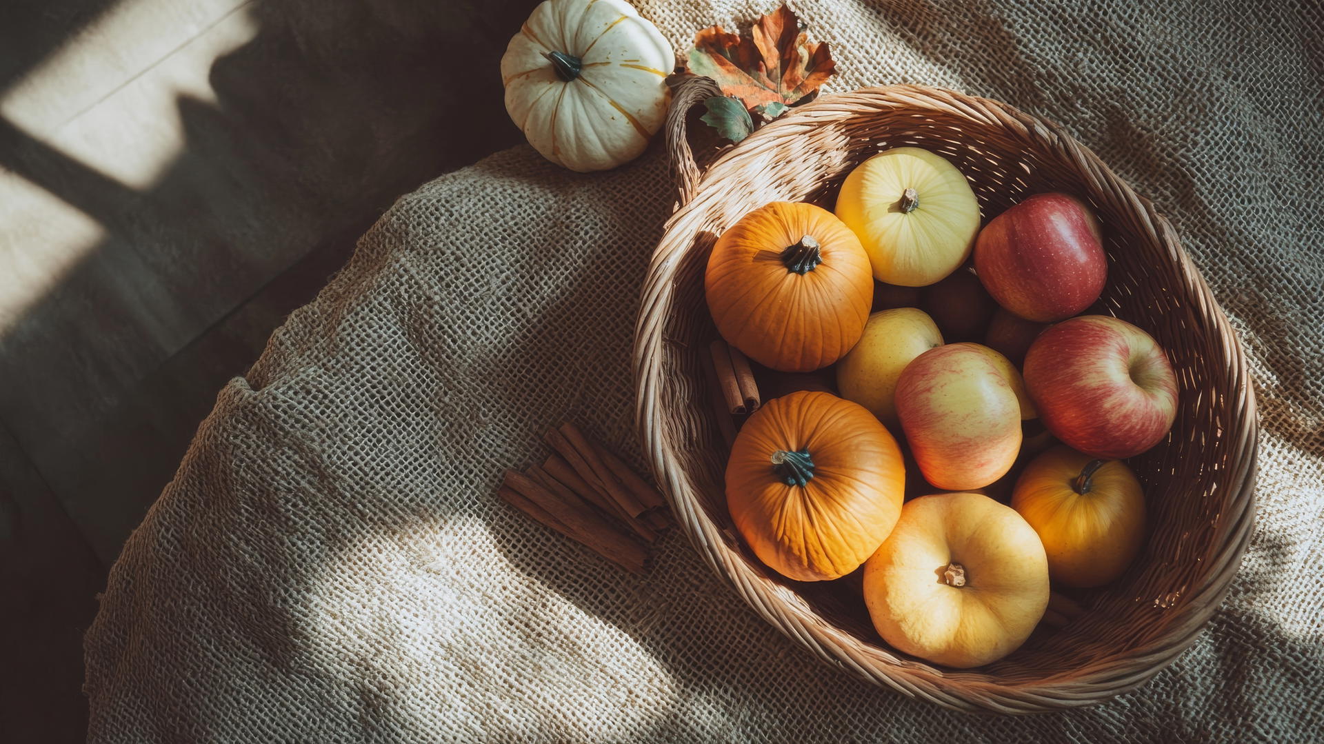 thanksgiving aesthetic wallpaper with squash, apples, and cinnamon in woven basket