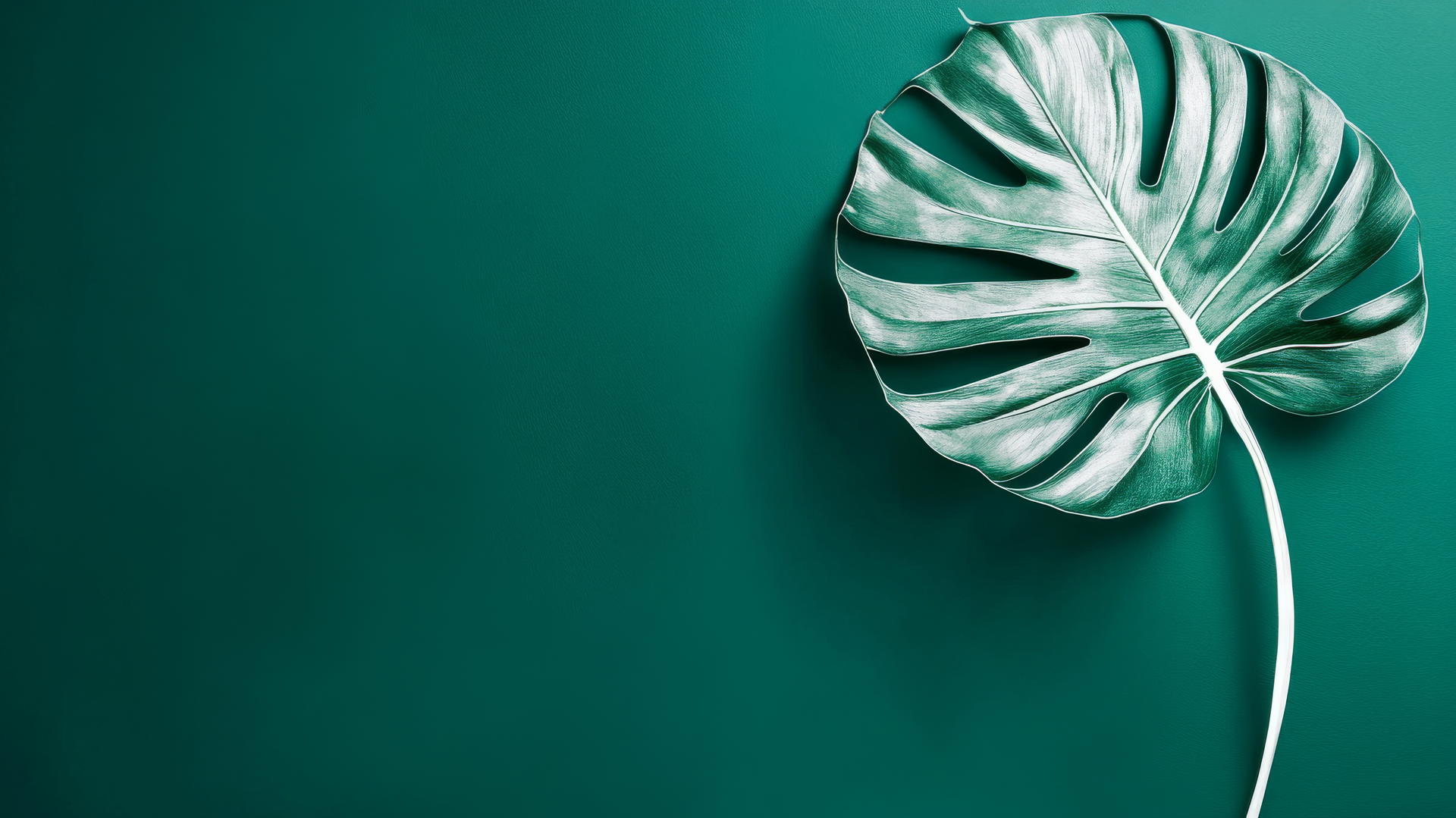 Emerald green wallpaper with a white monstera leaf silhouette