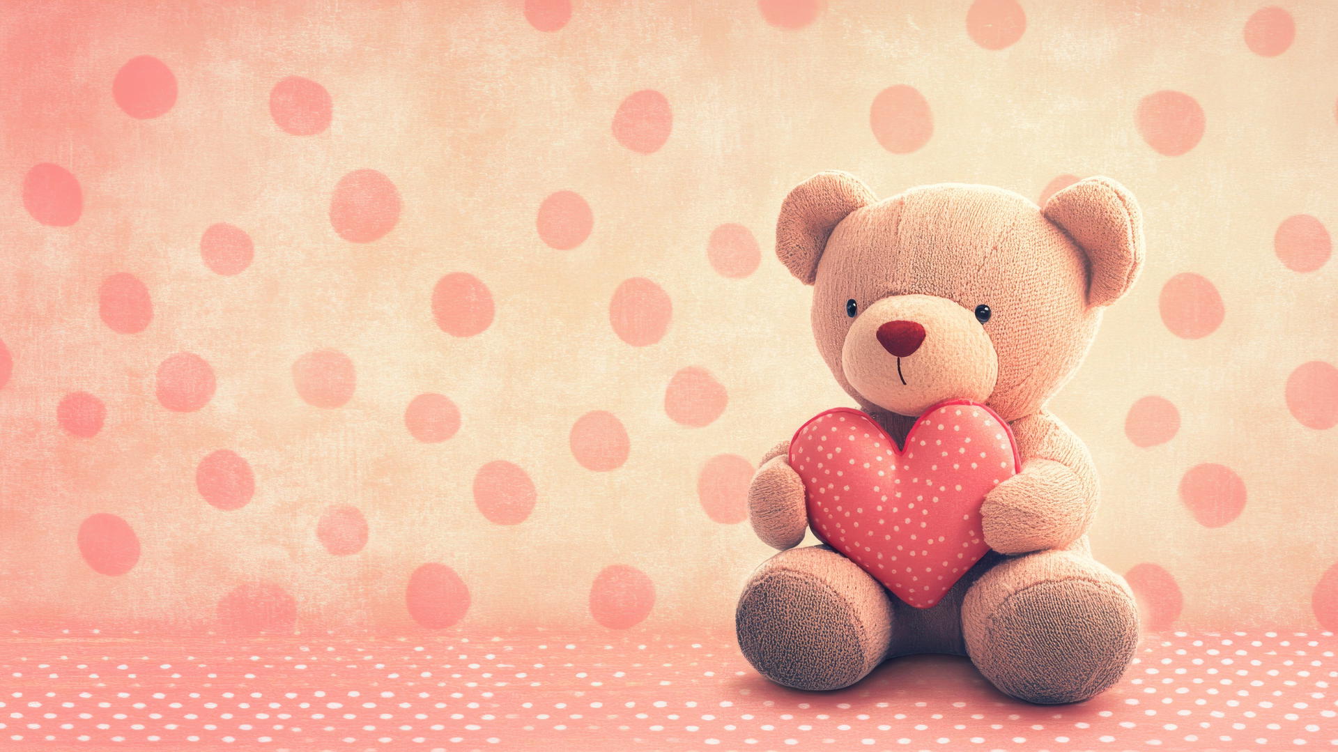 Pink cute wallpaper with teddy bear holding heart on polka-dotted background